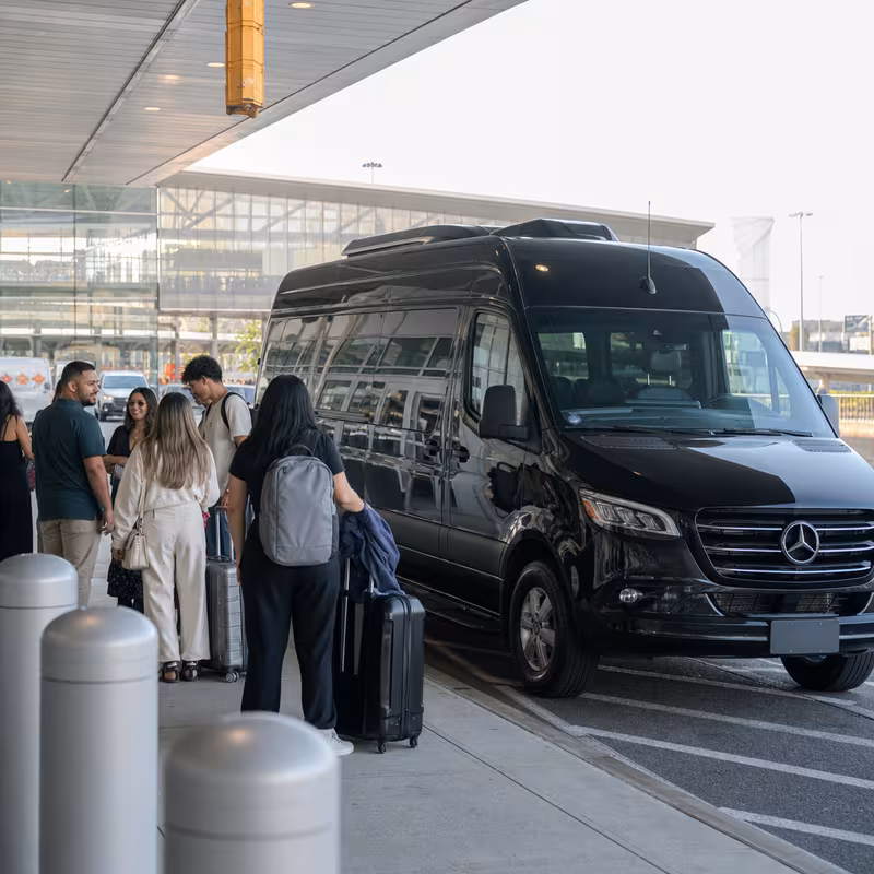 Group boarding a white charter bus for Airport Transportation transportation in Queens