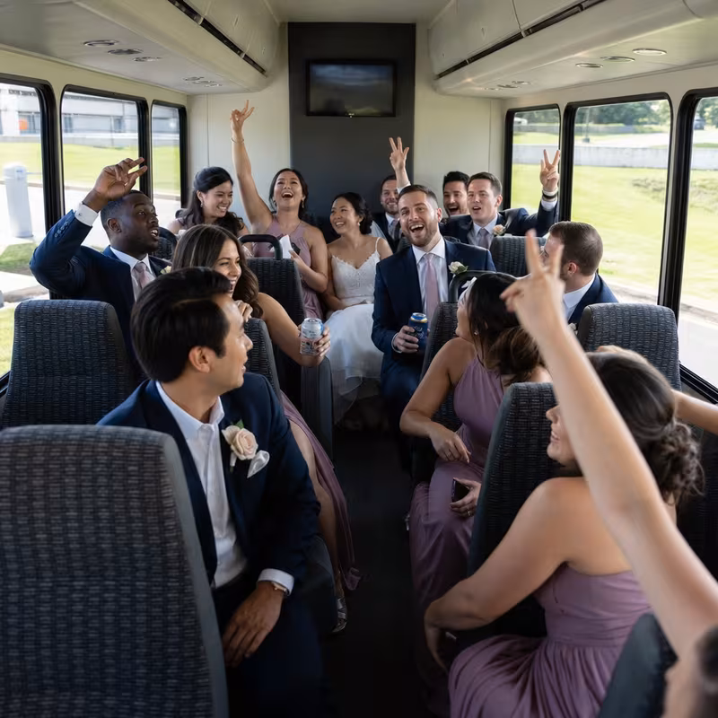 Group boarding a white charter bus for Wedding Transportation transportation in Queens
